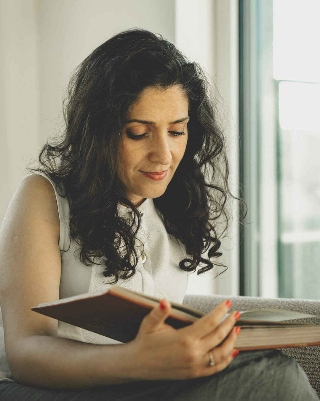 a-woman-sitting-on-a-couch-reading-a-book-9fjhsk4hmxs